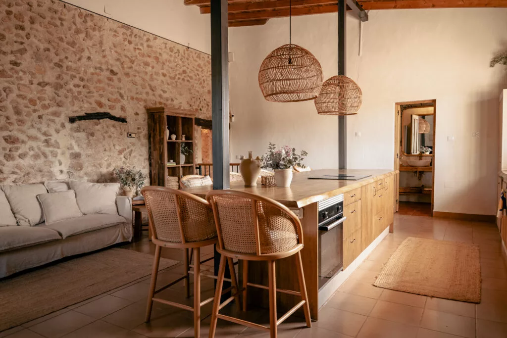 Salón cocina de Villa Andorina con isla, sofá y techo de vigas de madera