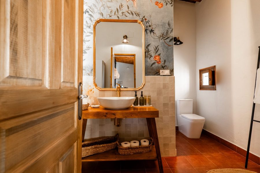 Baño con lavabo de madera, espejo y papel pintado