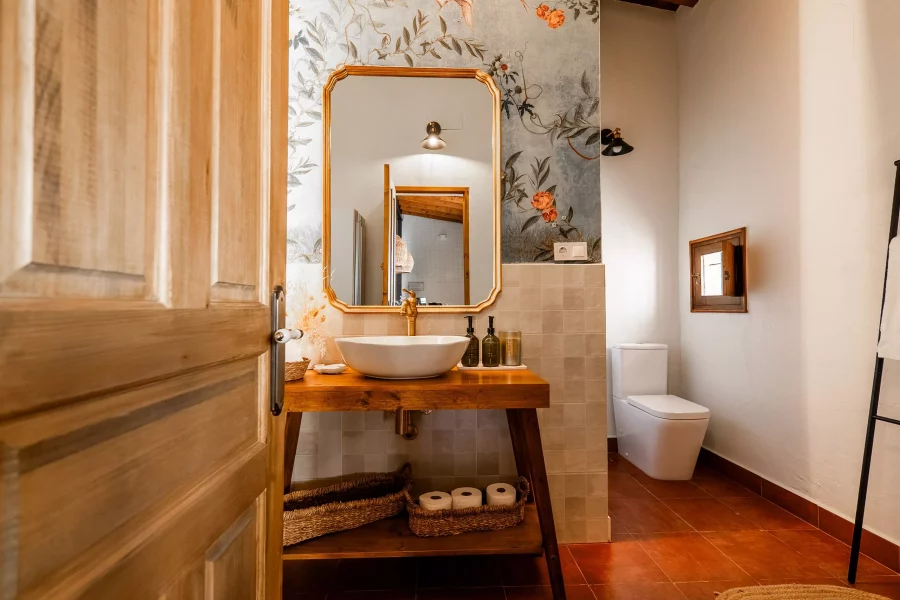 Baño con lavabo de madera, espejo y papel pintado