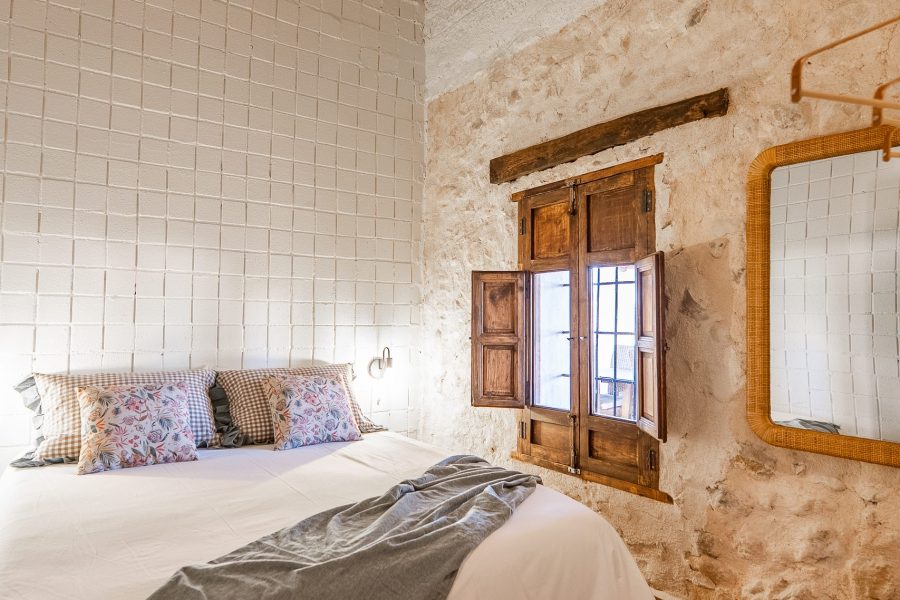 Dormitorio con pared de piedra y ventana de madera