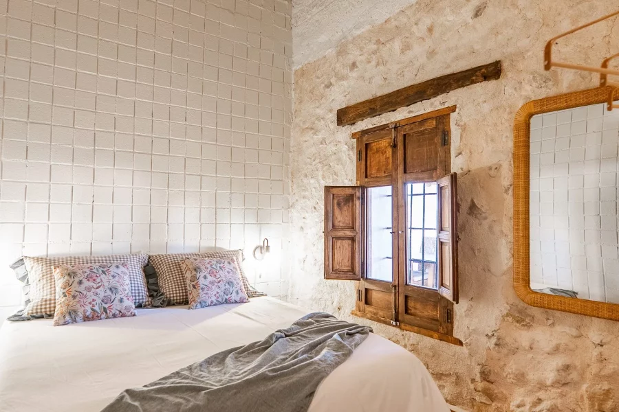 Dormitorio con pared de piedra y ventana de madera