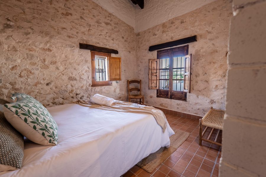 Dormitorio con dos ventanas y suelo de barro