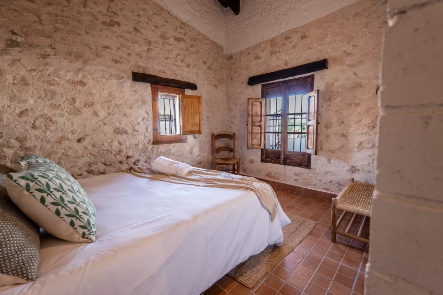 Dormitorio con dos ventanas y suelo de barro