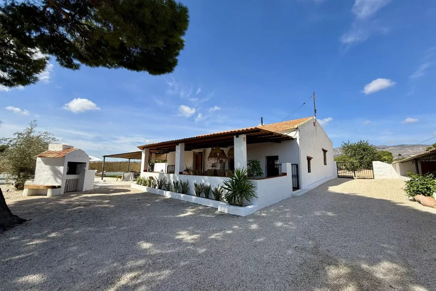 Fachada blanca de la casa entre los árboles