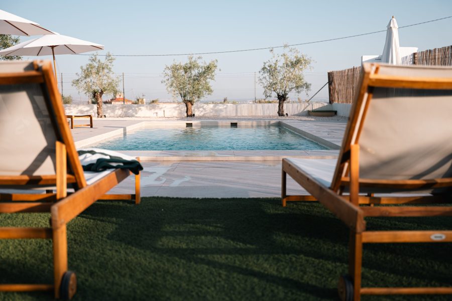 Piscina con hamacas de madera y sombrillas blancas