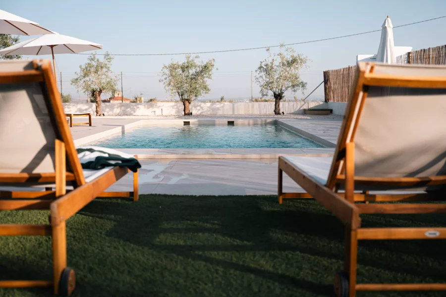 Piscina con hamacas de madera y sombrillas blancas