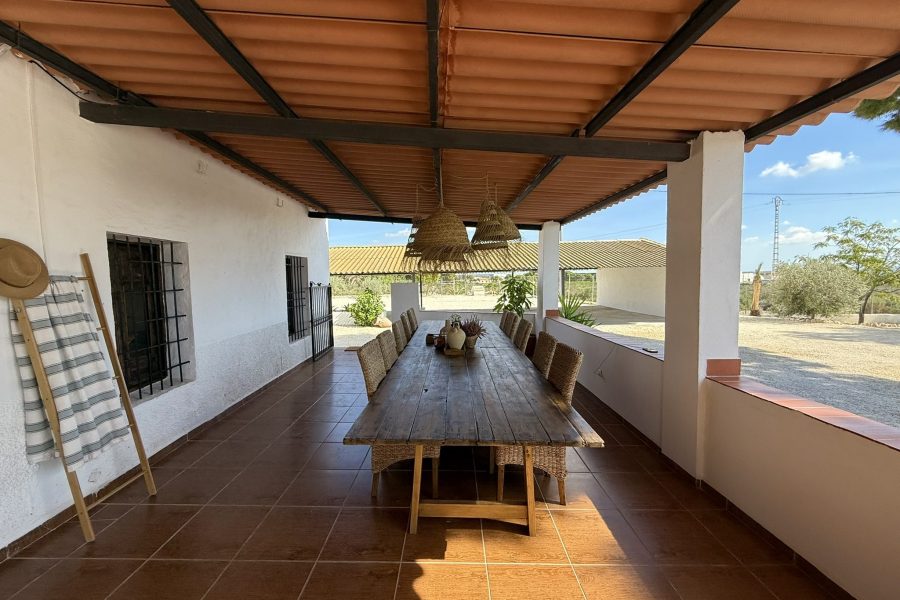 Mesa larga de madera bajo el porche de cañizo
